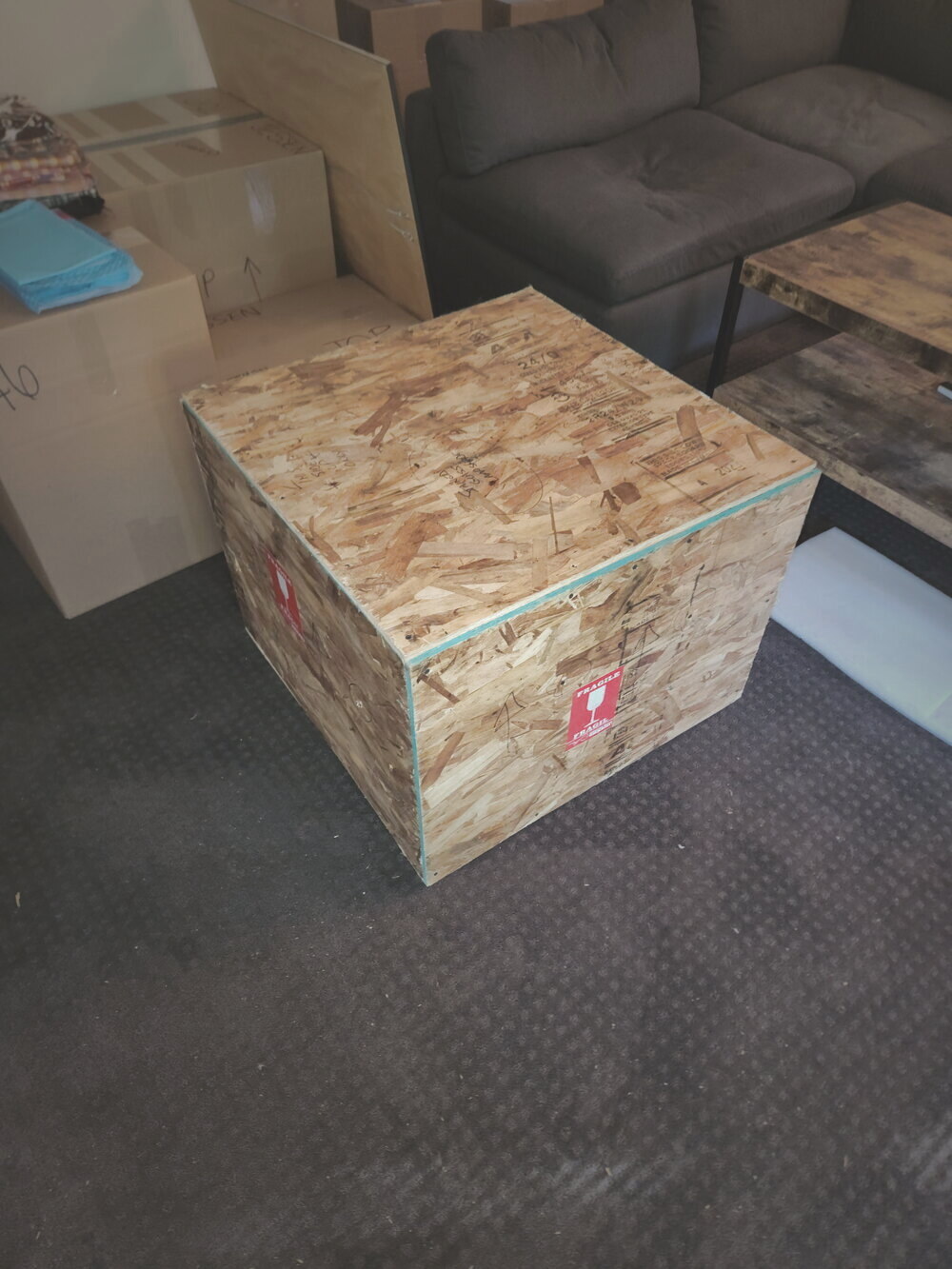 A sealed plywood crate marked fragile, built on-site in a client's living room