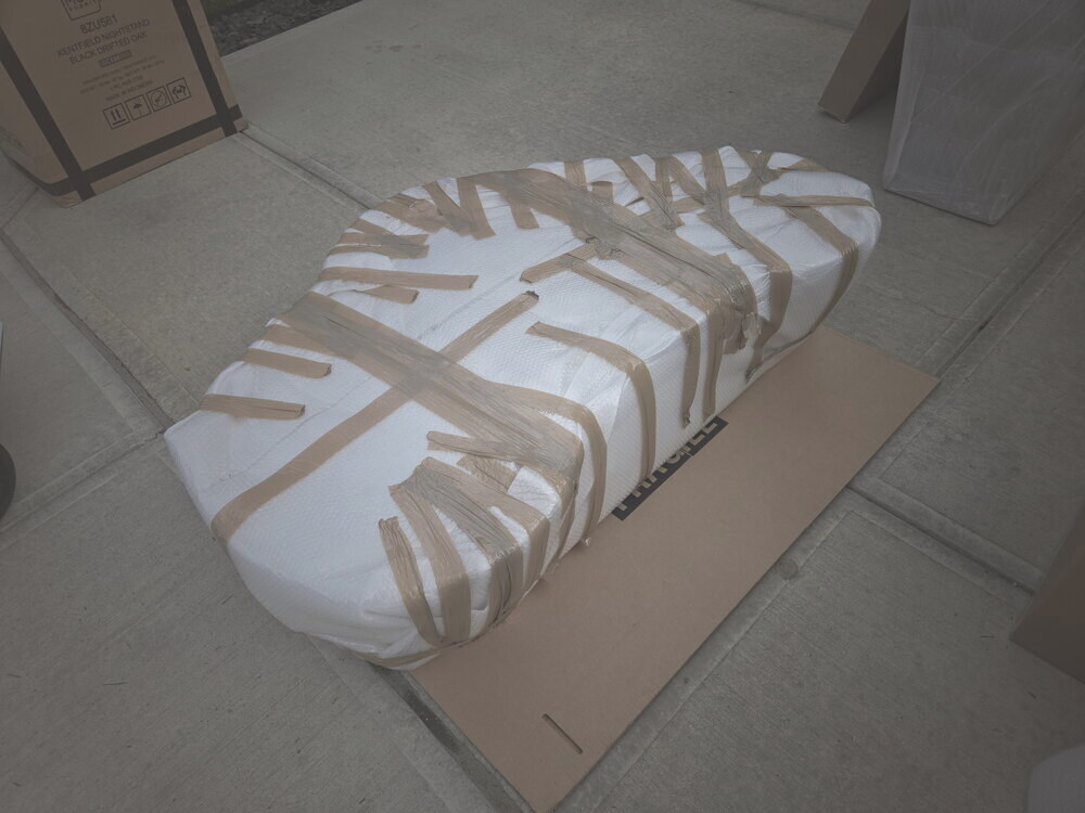 A figure-eight Carrara marble table top wrapped and taped, braced flat for transport